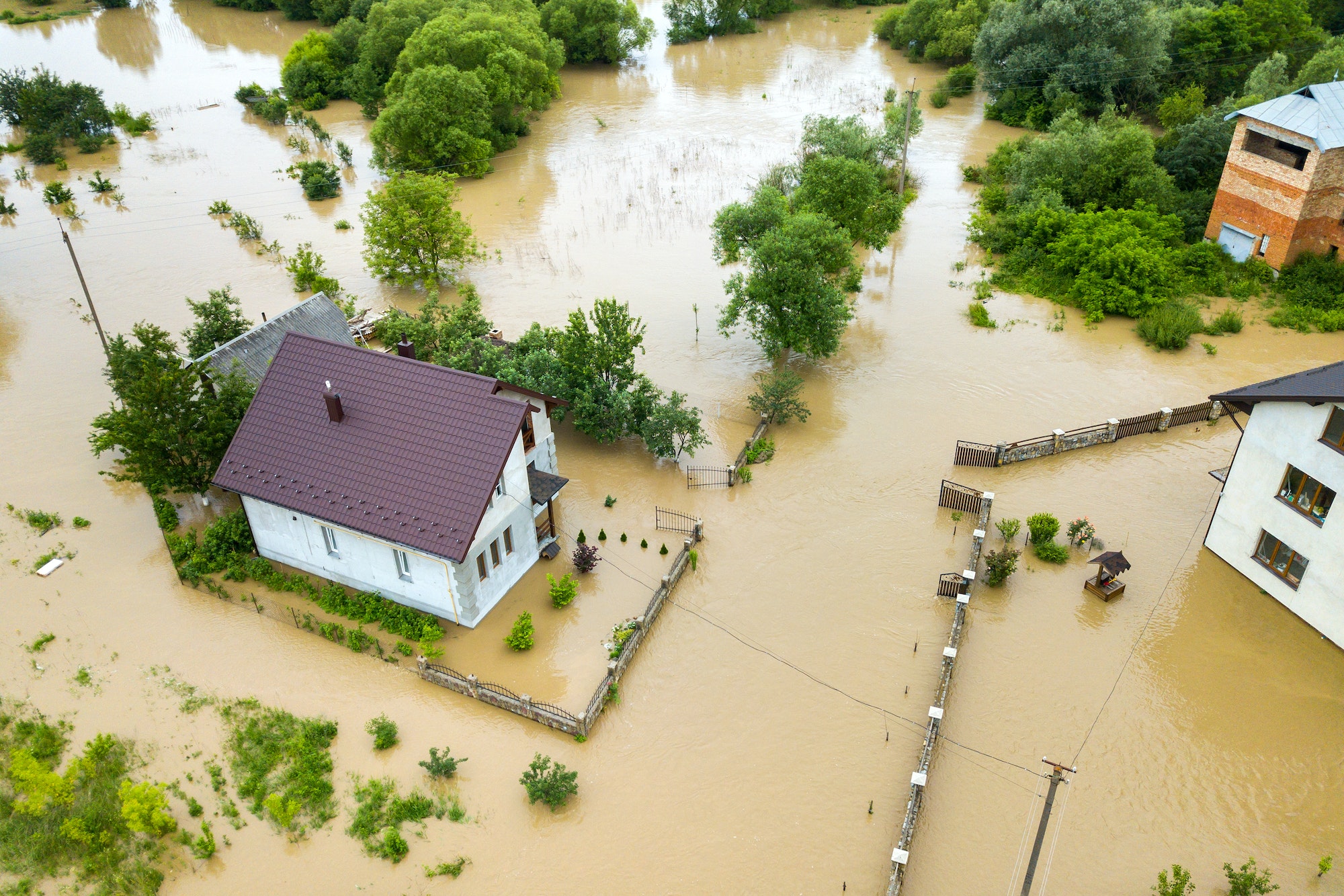 Aerial view of flooded house with dirty water all around it.